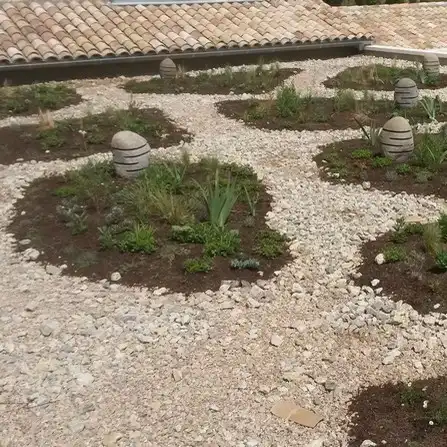 Toiture végétalisée aménagée avec des plantes, du gravier clair et des éclairages extérieurs
